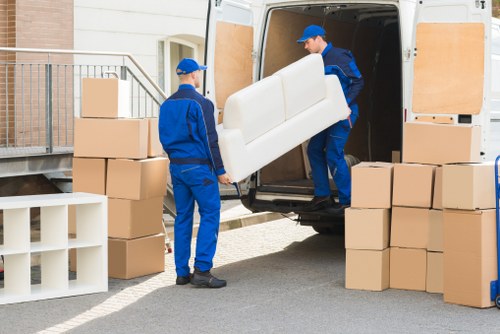 Local removals team carrying furniture through a narrow London stairwell