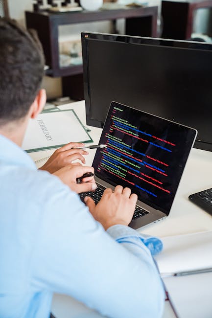 Close-up view of a computer screen displaying many lines of programming code with syntax highlighting in various colors, including pink, yellow, green, and blue. The code contains functions, variables